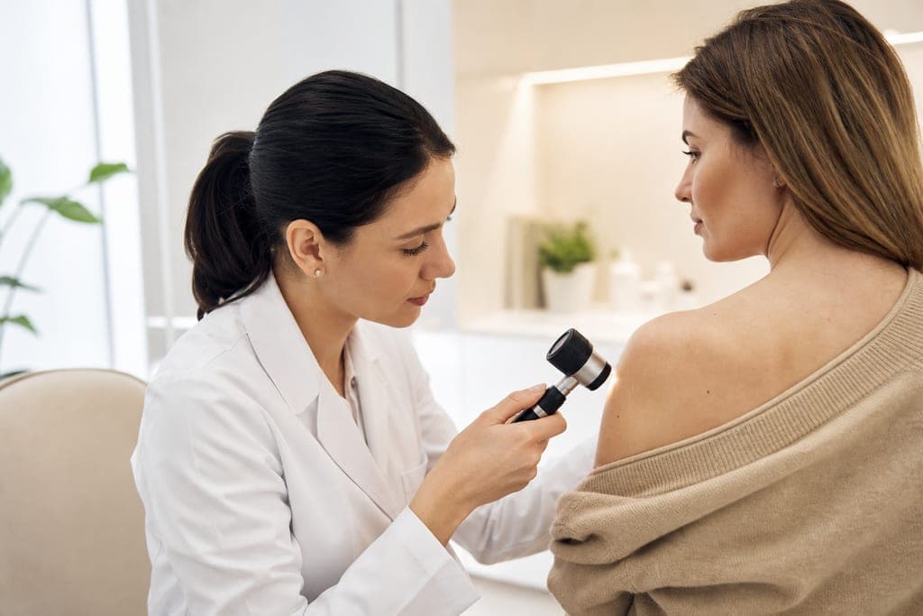 Dermatologist examining a patient's skin with a dermatoscope in a modern clinic