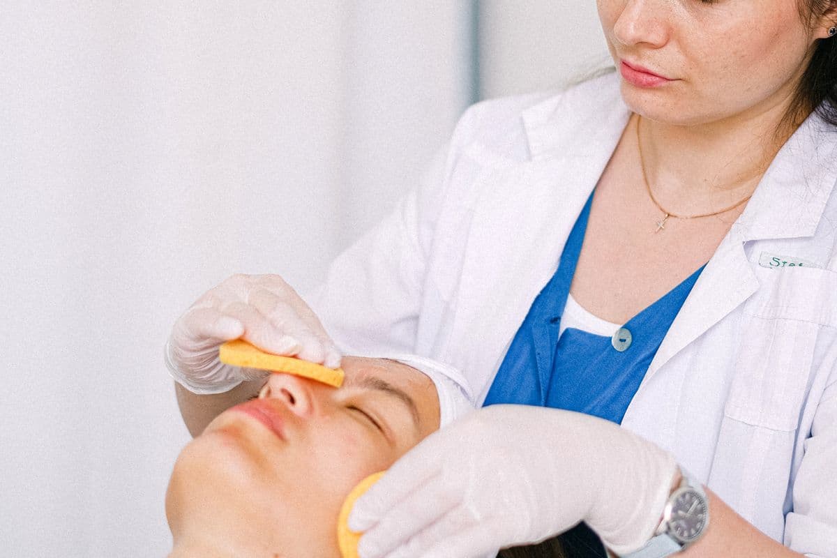 Med spa aesthetician in a white coat performing a professional facial treatment