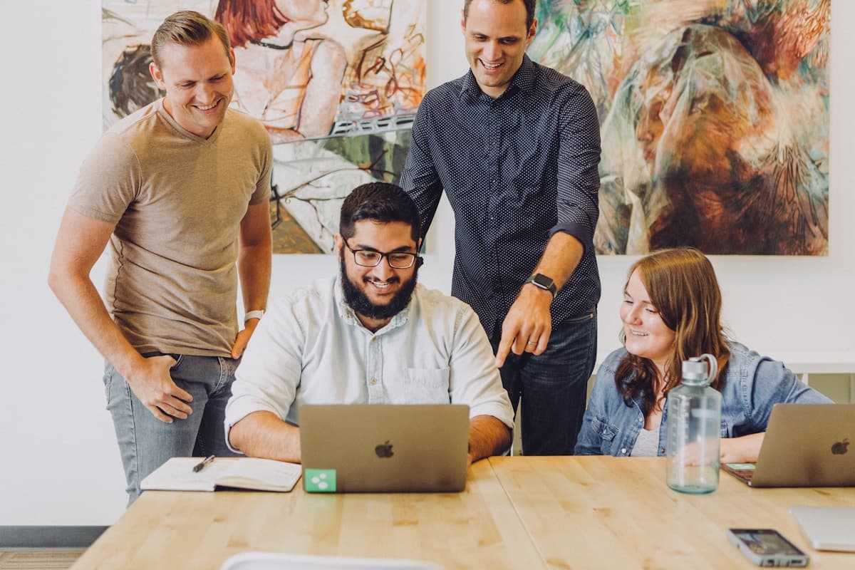 Happy marketing team collaborating around a laptop in a creative agency